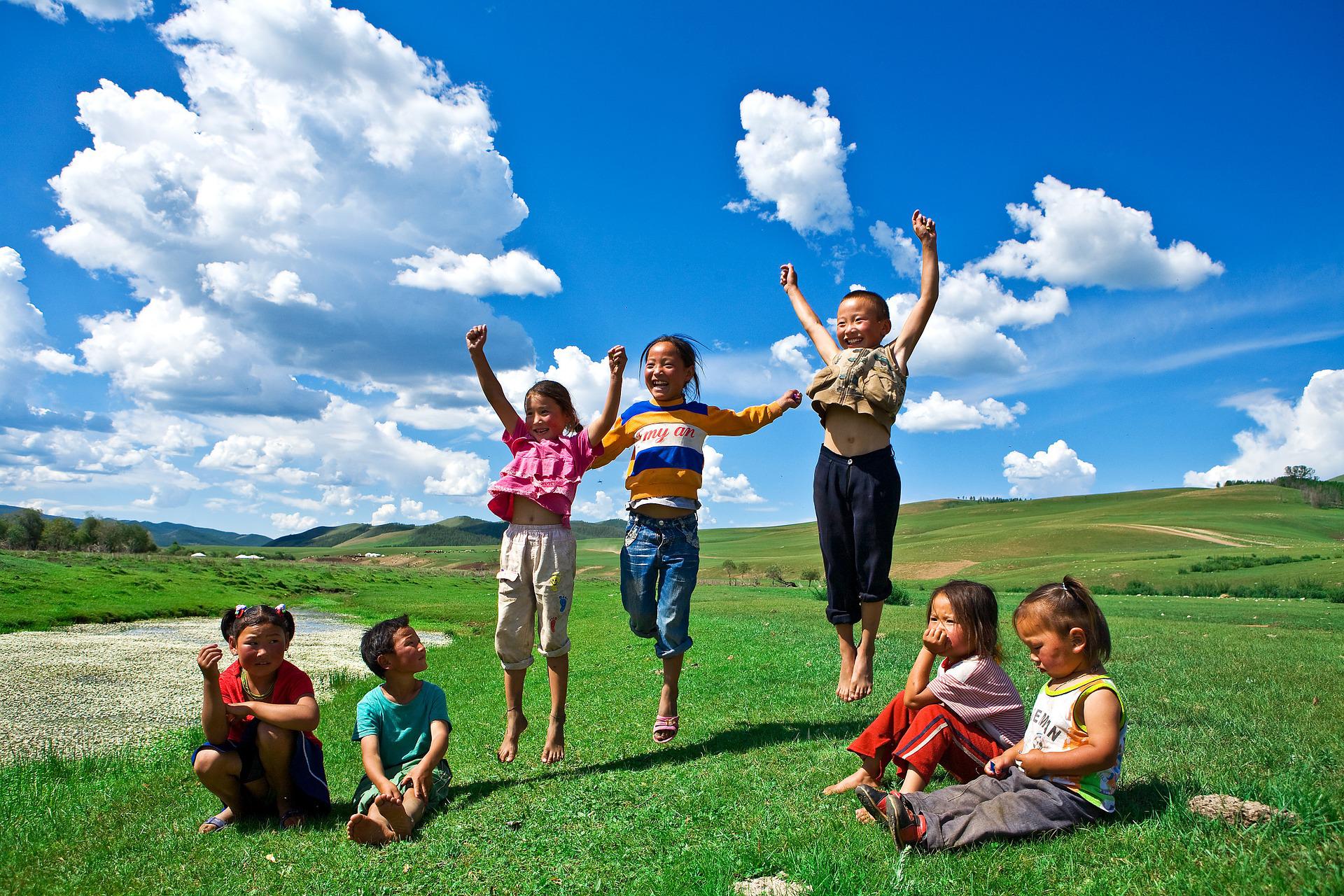Mongolian children sitting and jumping in nature